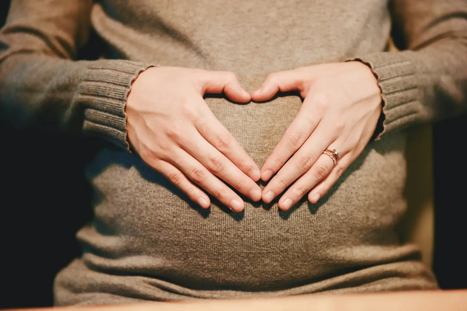 Expectant mother with hands forming a heart
